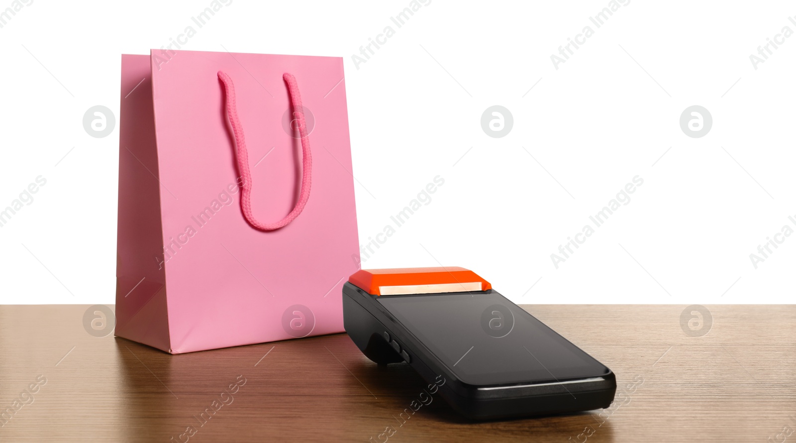 Photo of Payment terminal and shopping bag on wooden table against white background