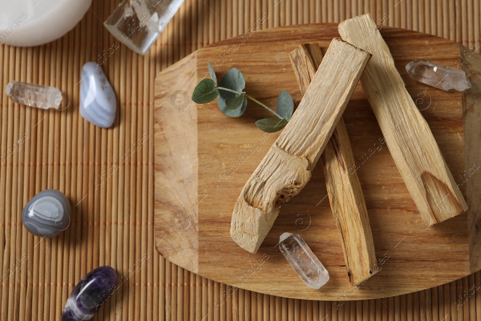 Photo of Palo santo sticks and gemstones on wicker table, flat lay