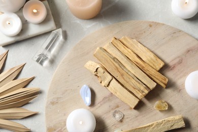 Photo of Palo santo sticks and gemstones on light table, flat lay