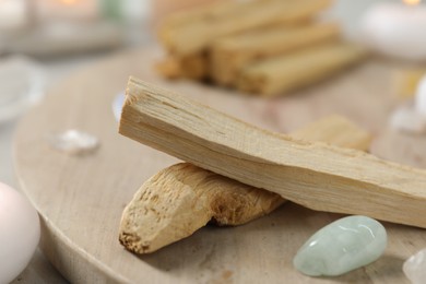 Photo of Palo santo sticks and gemstones on table, closeup