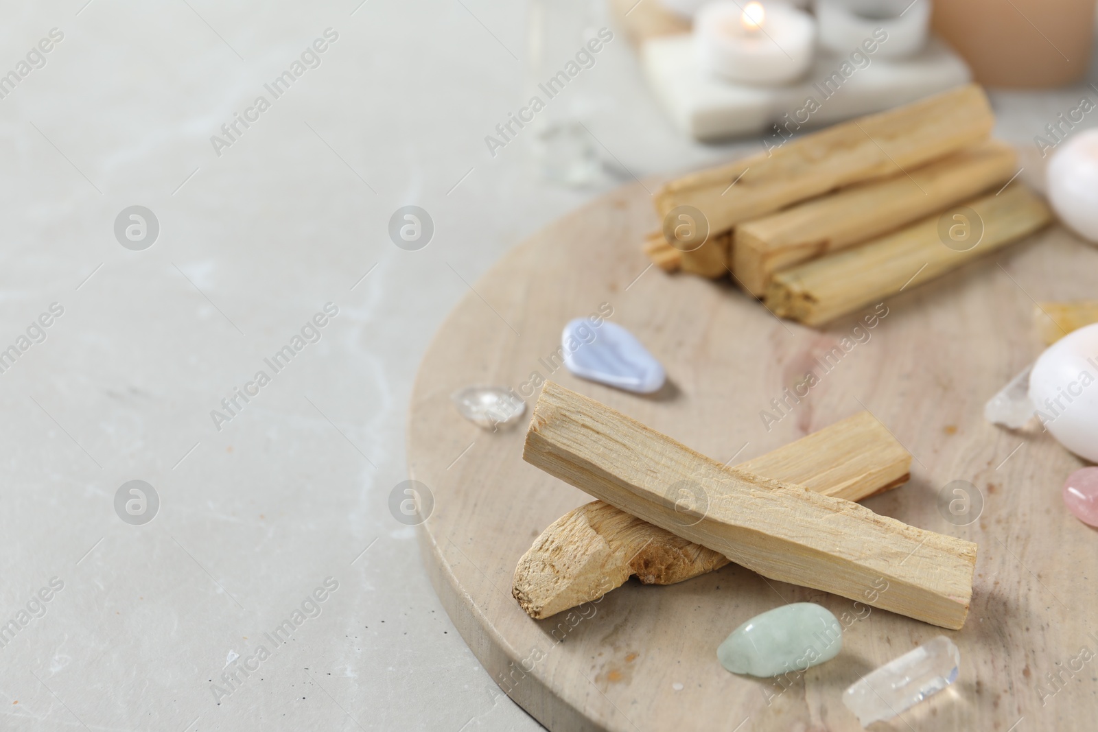 Photo of Palo santo sticks and gemstones on light table. Space for text