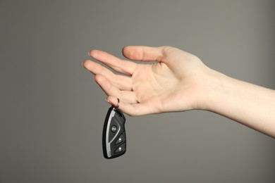 Photo of Woman with car flip key on grey background, closeup. Space for text