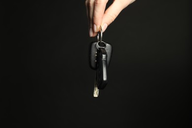 Woman with car keys on black background, closeup