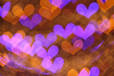 Photo of Romantic decor. Blurred view of heart shaped lights on color background, bokeh effect