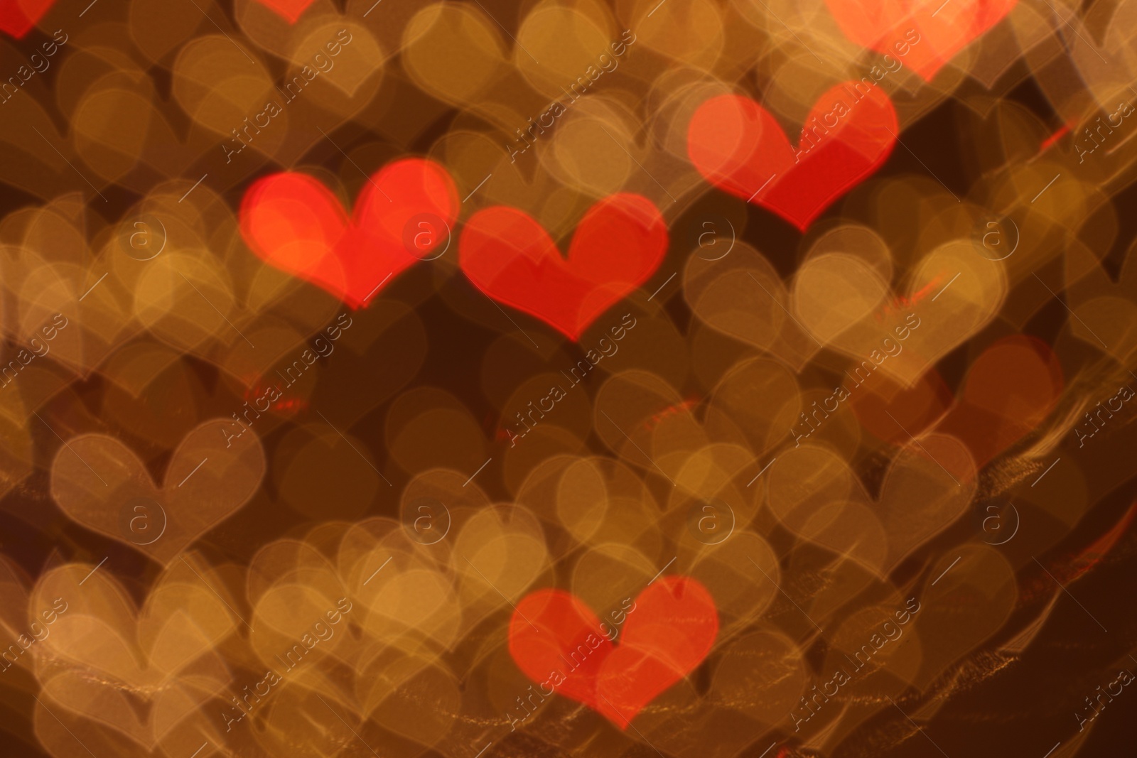 Photo of Romantic decor. Blurred view of heart shaped lights on color background, bokeh effect