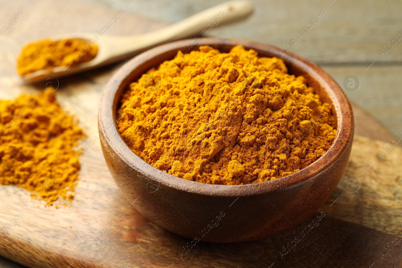 Photo of Turmeric powder in bowl on table, closeup