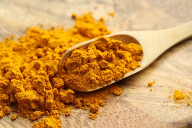 Photo of Turmeric powder and spoon on table, closeup