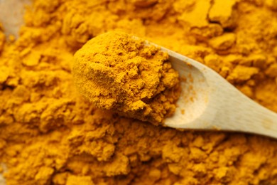 Photo of Turmeric powder and spoon on table, closeup