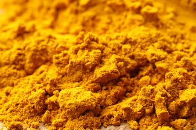 Photo of Heap of turmeric powder on table, closeup