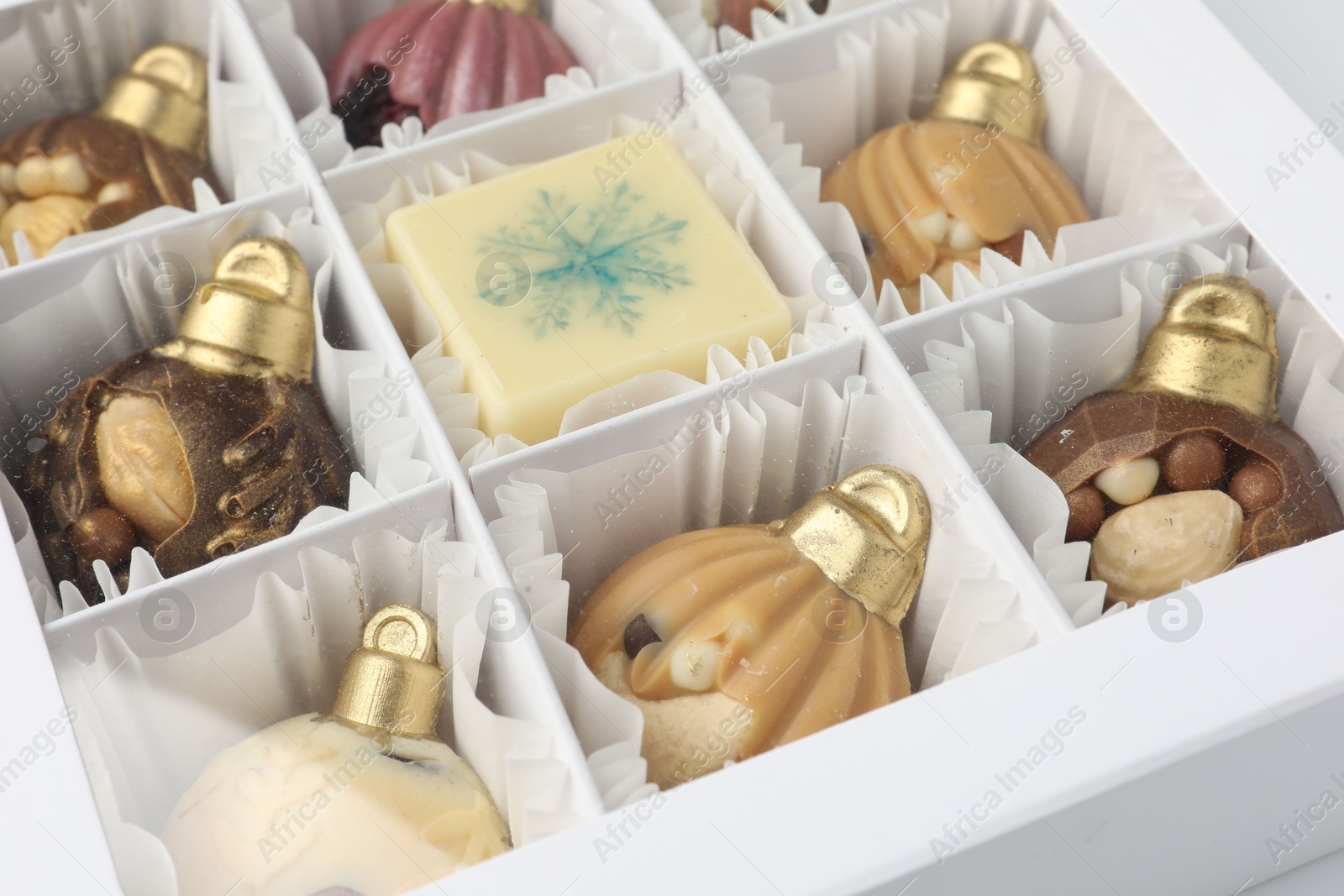 Photo of Box with delicious chocolate in shape of Christmas ornaments, closeup