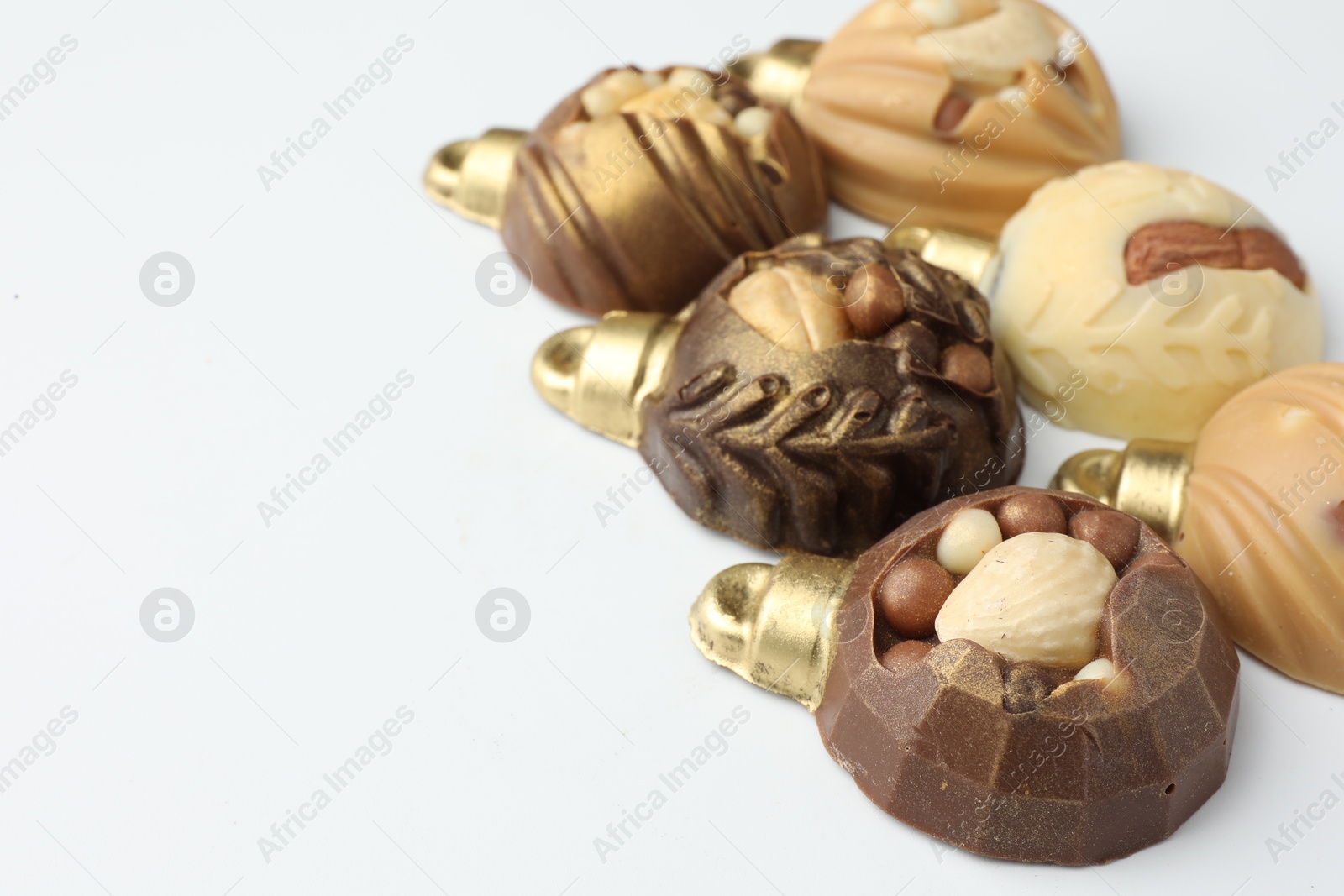 Photo of Delicious chocolate in shape of Christmas baubles on white background, closeup. Space for text