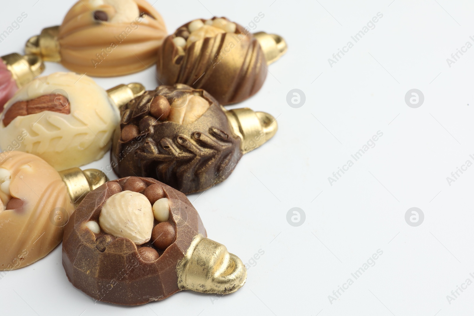 Photo of Delicious chocolate in shape of Christmas baubles on white background, closeup. Space for text