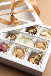 Photo of Delicious chocolate in shape of Christmas ornaments in open box on beige background, closeup