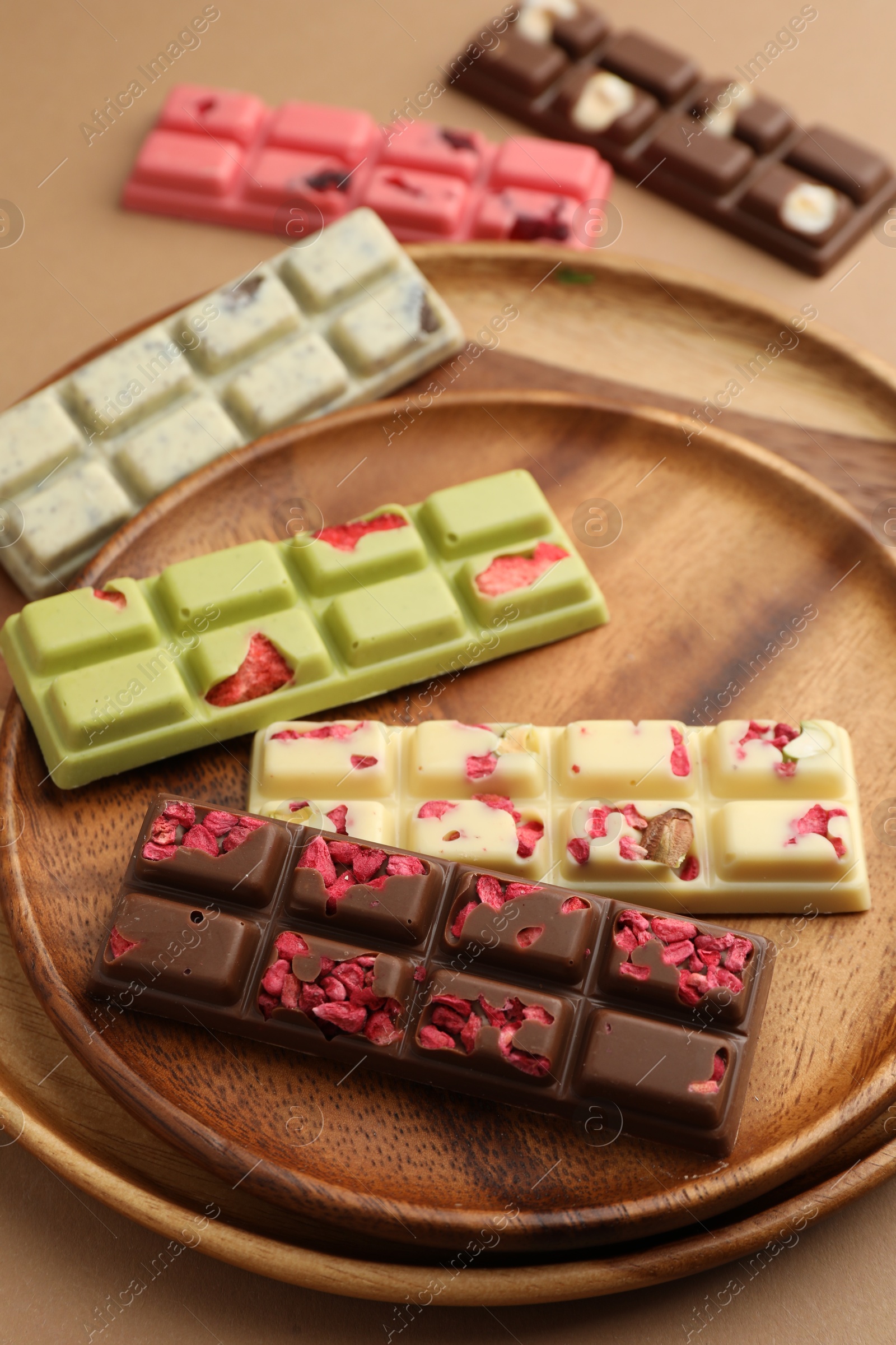 Photo of Different tasty chocolate bars on beige background, closeup