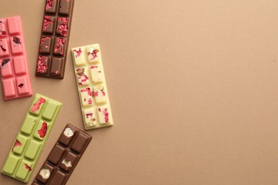 Photo of Different tasty chocolate bars on beige background, flat lay. Space for text