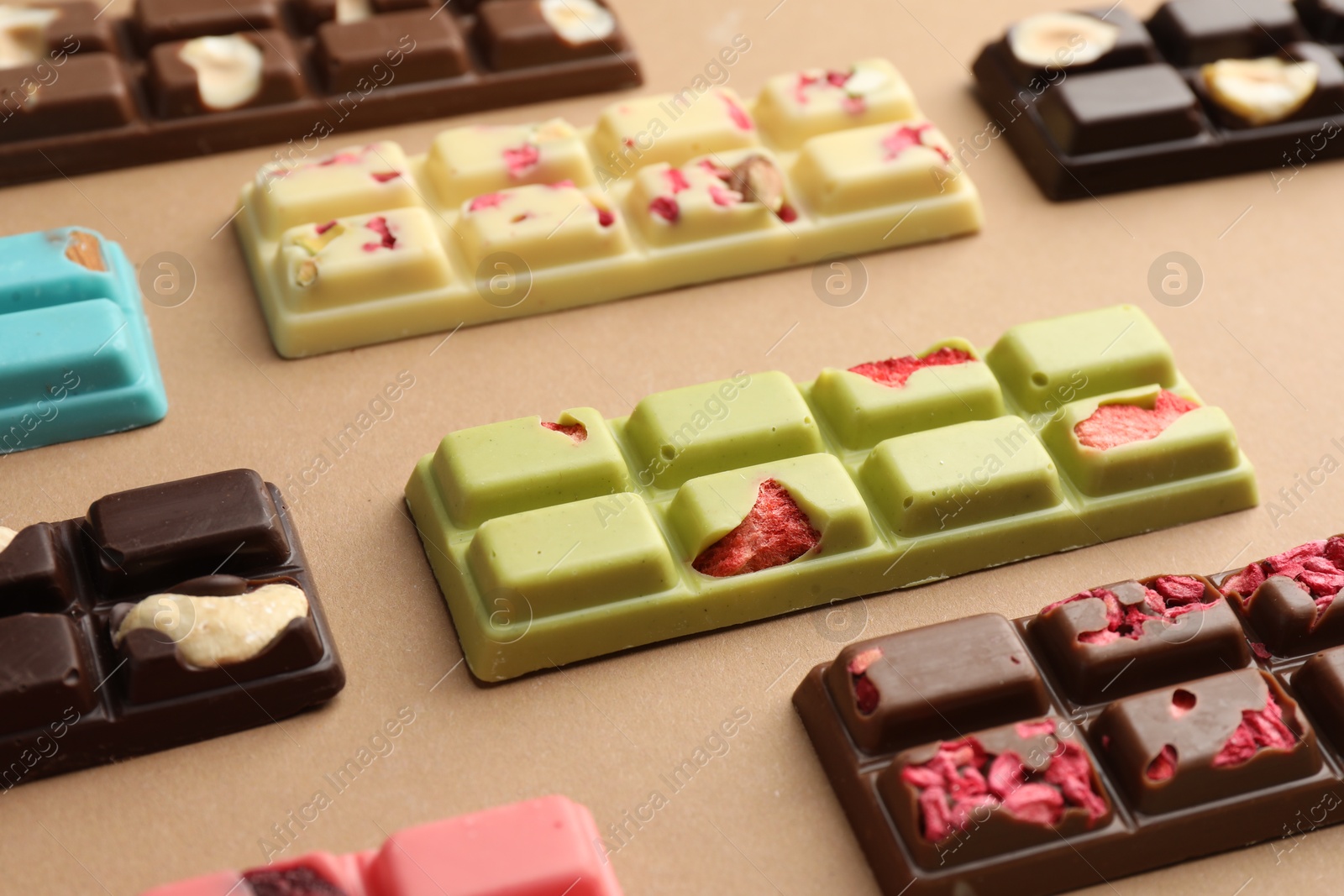 Photo of Different tasty chocolate bars on beige background, closeup