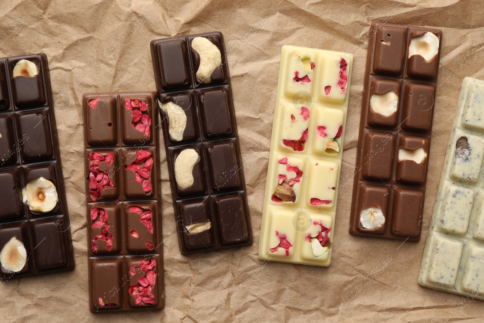 Photo of Different tasty chocolate bars on crumpled parchment, top view