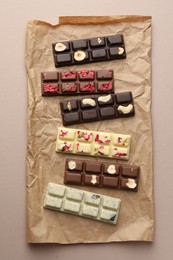 Photo of Different tasty chocolate bars on beige background, top view