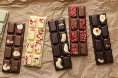 Photo of Different tasty chocolate bars on crumpled parchment, top view