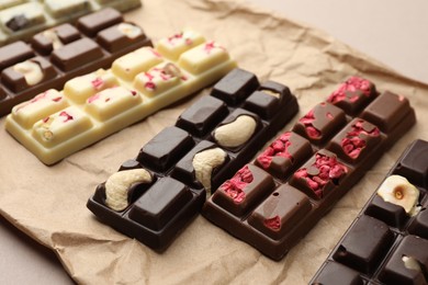 Photo of Different tasty chocolate bars on beige background, closeup