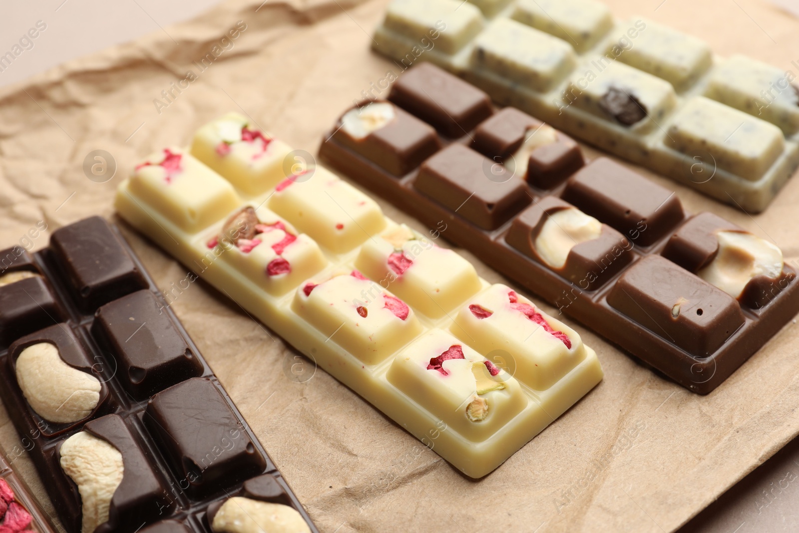 Photo of Different tasty chocolate bars on beige background, closeup