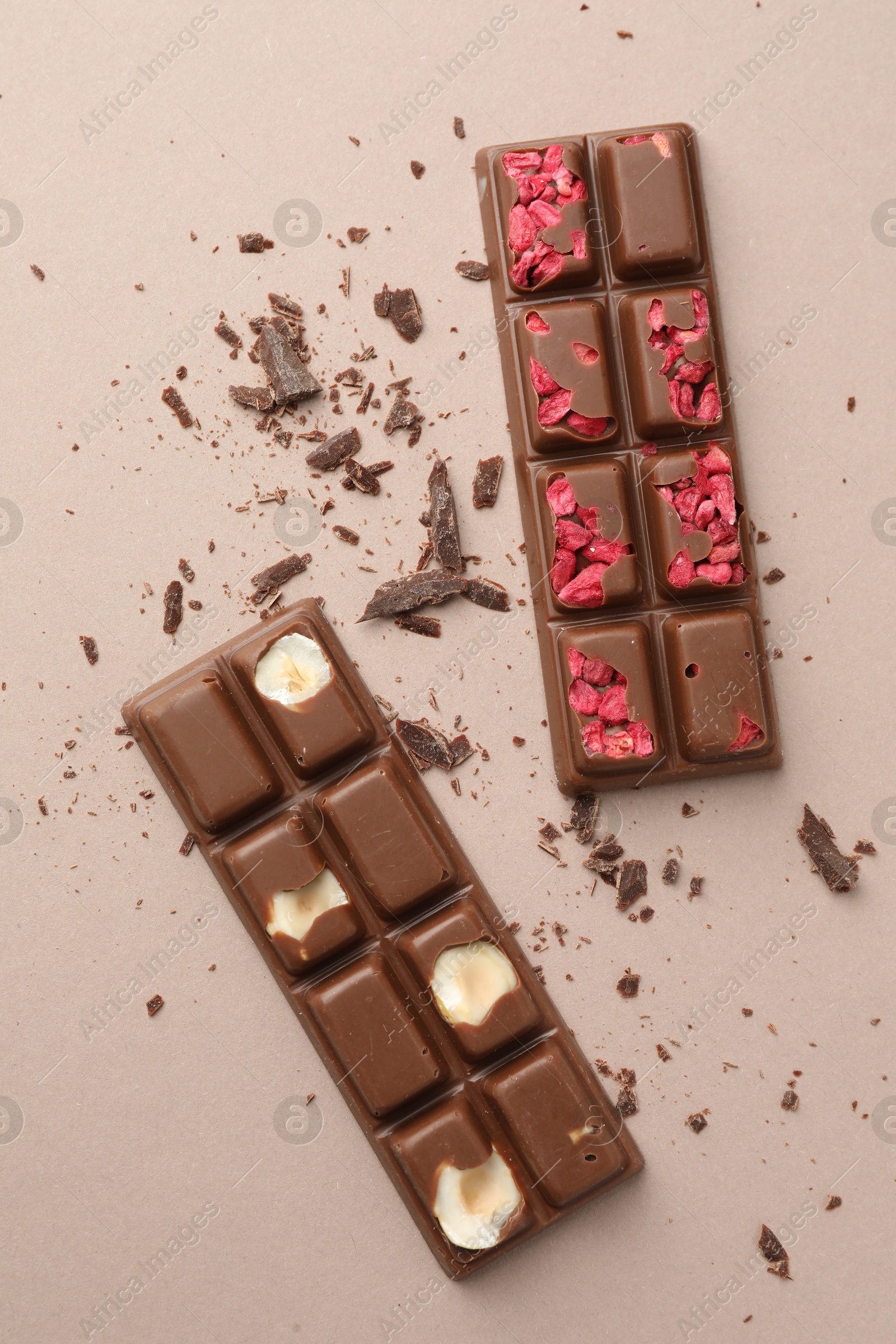 Photo of Tasty chocolate bars and crumbs on beige background, flat lay