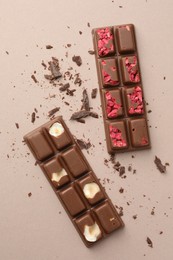 Photo of Tasty chocolate bars and crumbs on beige background, flat lay