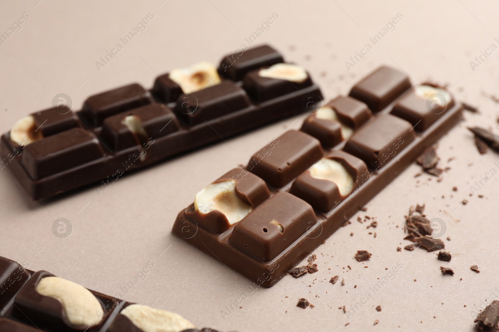 Photo of Tasty chocolate bars and crumbs on beige background, closeup