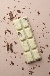 Photo of Tasty chocolate bar and crumbs on beige background, top view