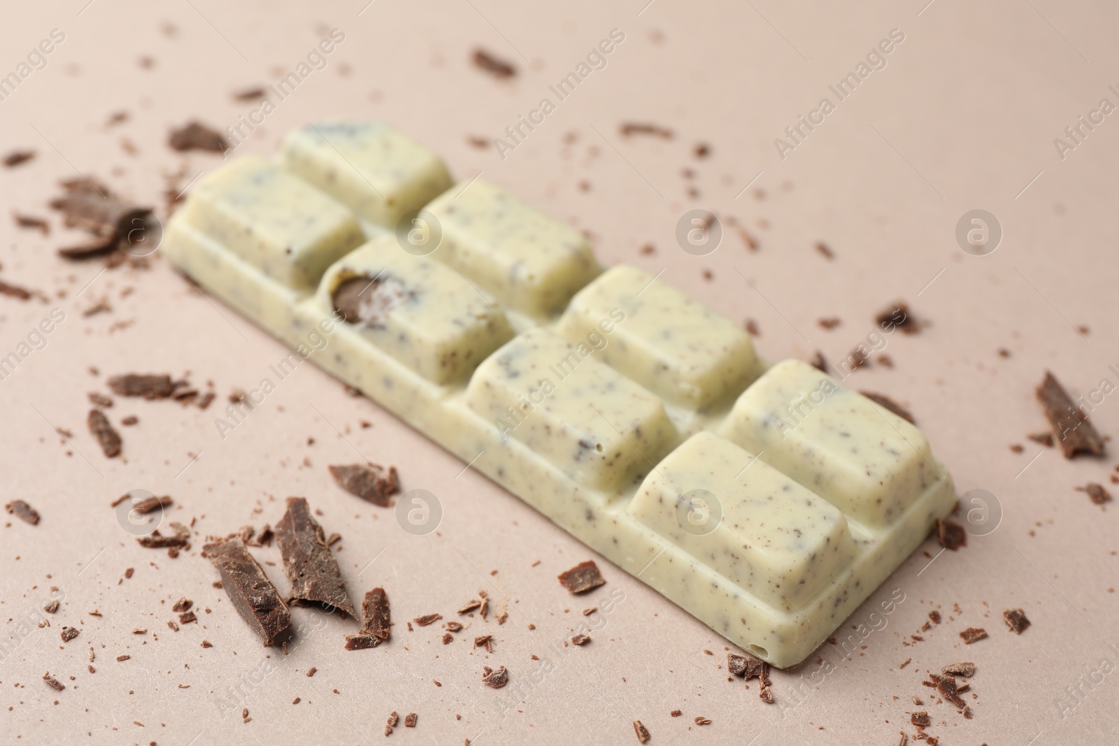 Photo of Tasty chocolate bar and crumbs on beige background, closeup