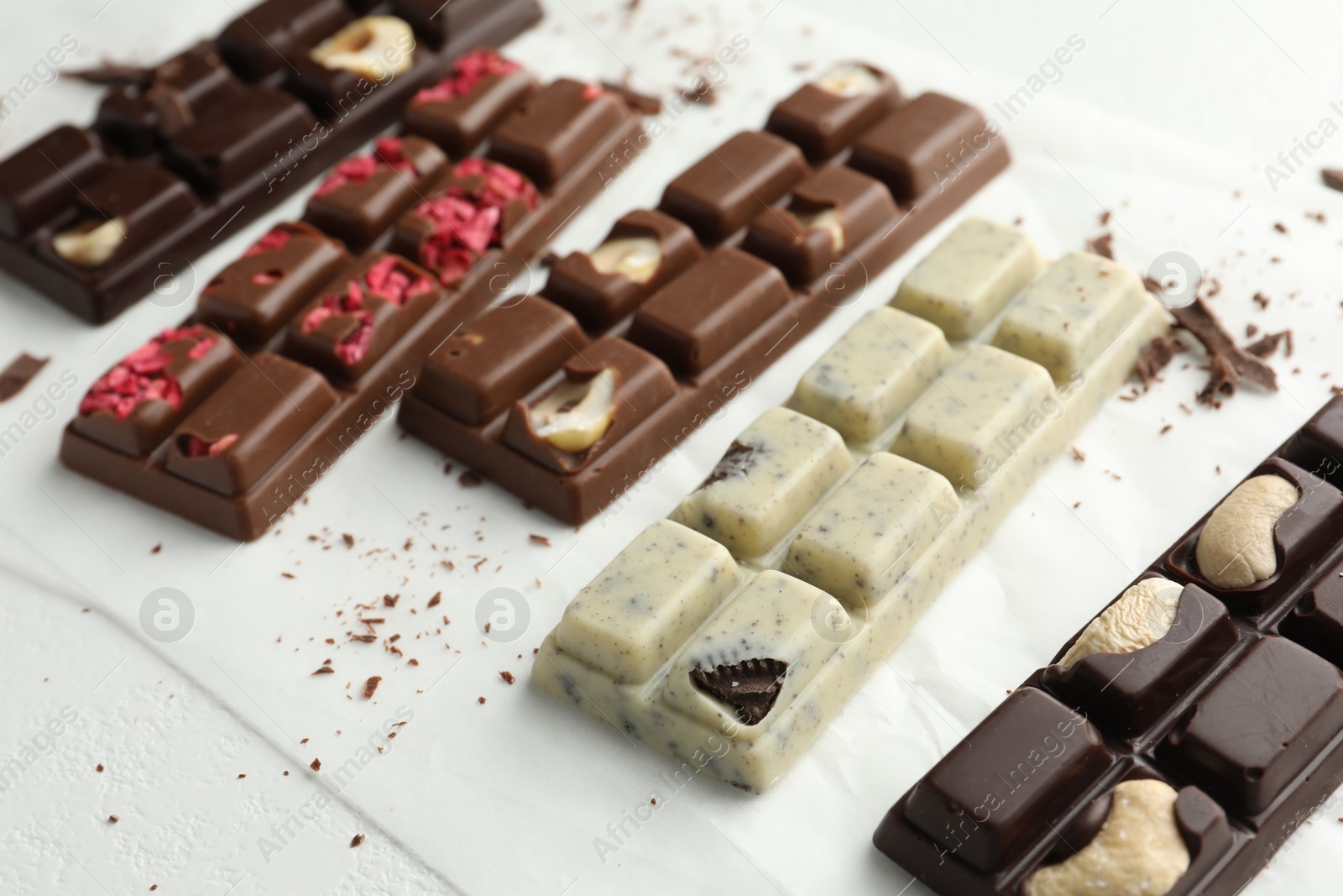 Photo of Tasty chocolate bars and crumbs on white background, closeup