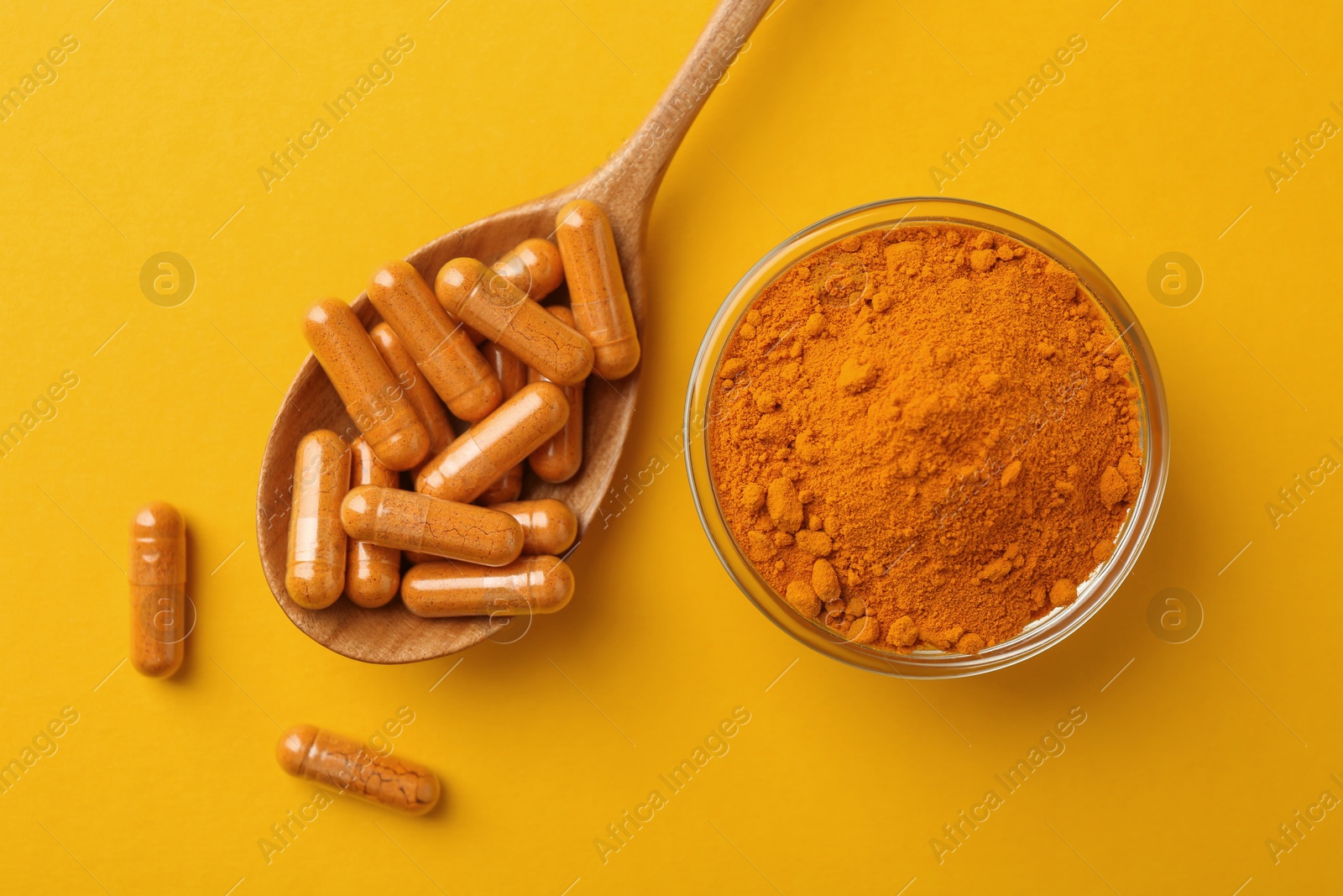 Photo of Many turmeric capsules and powder on yellow background, flat lay