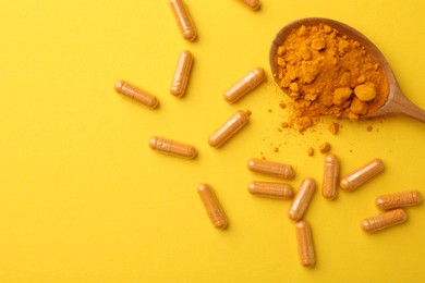 Photo of Many turmeric capsules and powder on yellow background, flat lay. Space for text