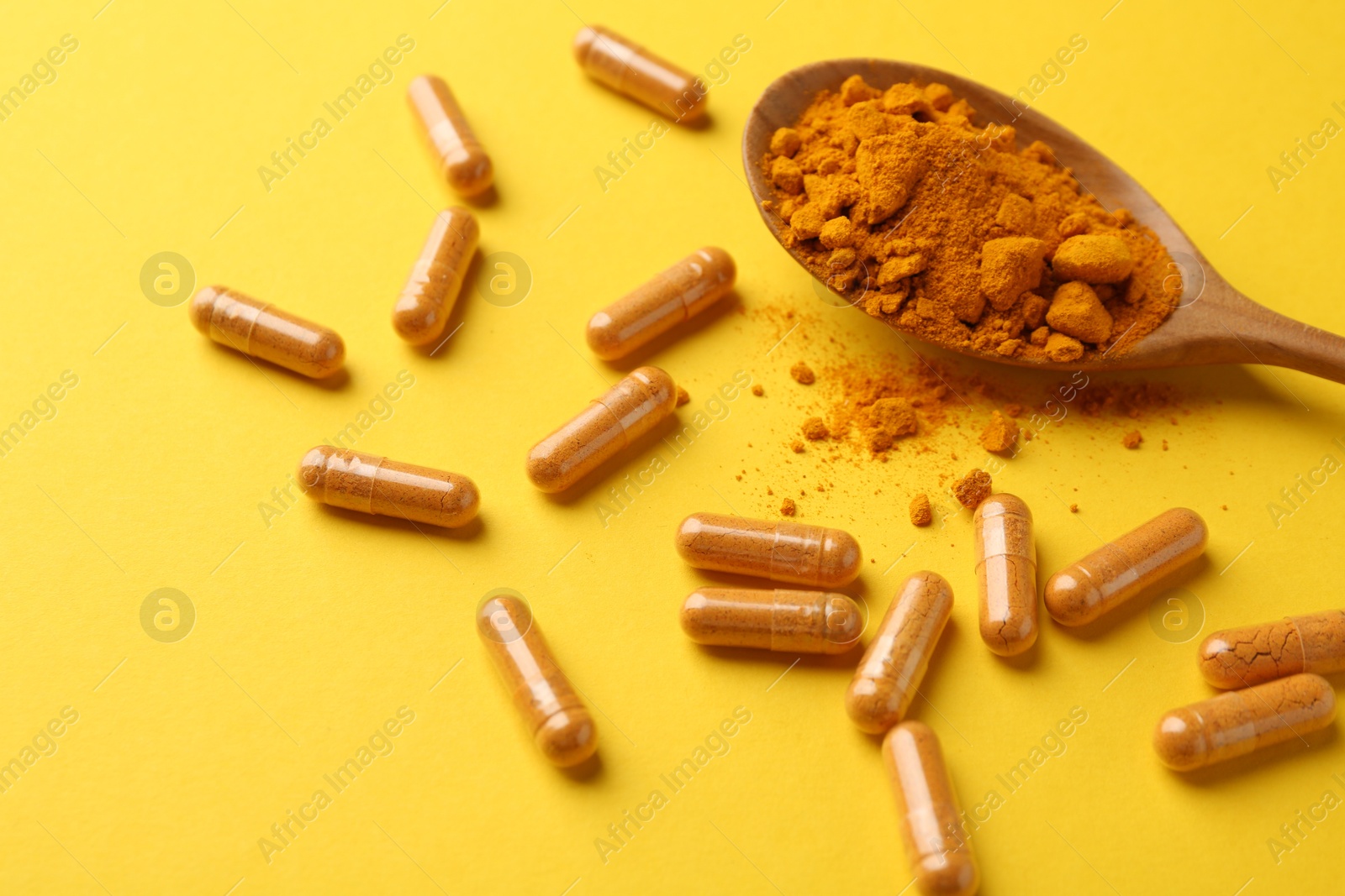 Photo of Many turmeric capsules and powder on yellow background, closeup