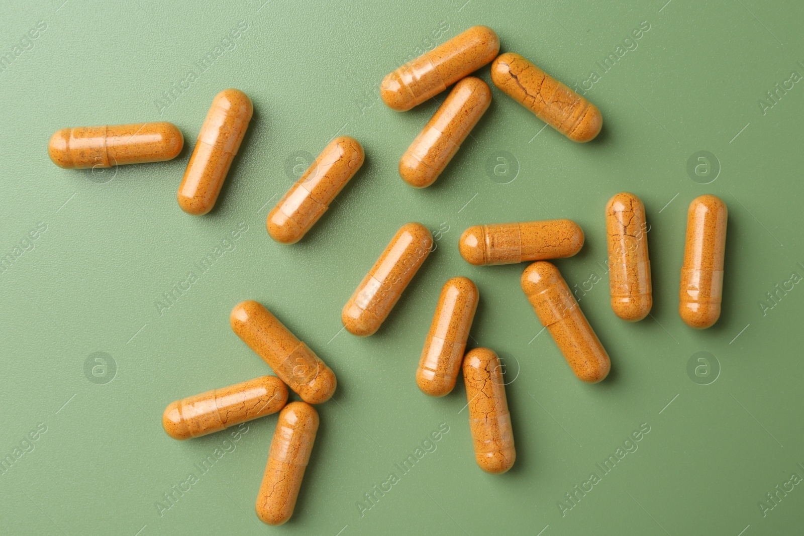 Photo of Many turmeric capsules on light green background, flat lay