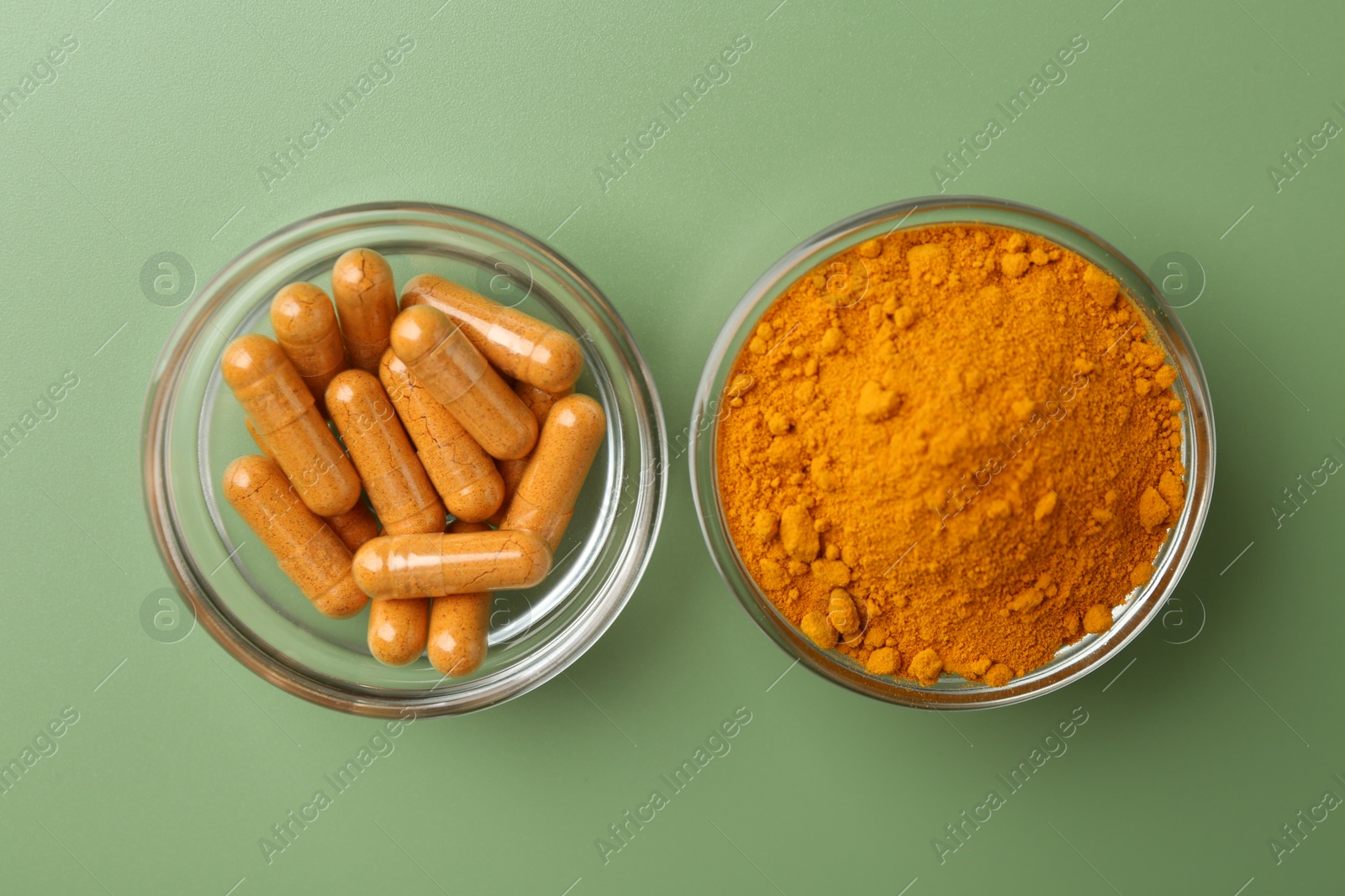 Photo of Many turmeric capsules and powder on light green background, top view