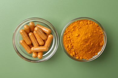 Photo of Many turmeric capsules and powder on light green background, top view