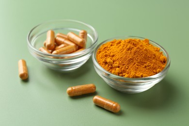 Photo of Many turmeric capsules and powder on light green background, closeup