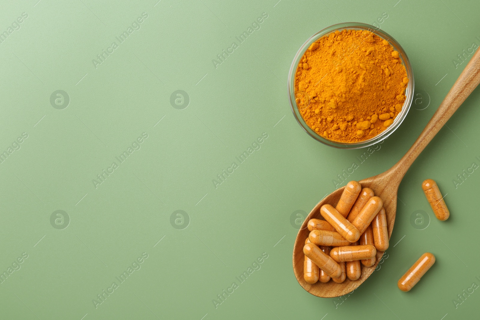 Photo of Many turmeric capsules and powder on light green background, flat lay. Space for text