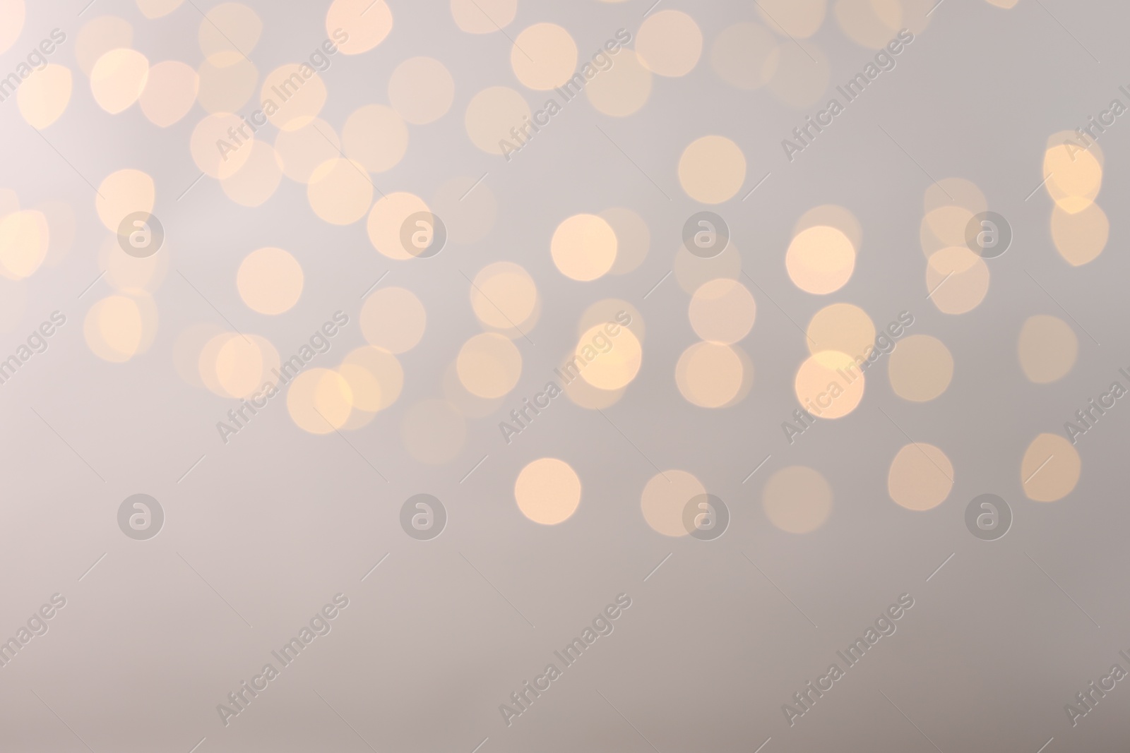 Photo of Blurred view of golden lights on light background, space for text. Bokeh effect