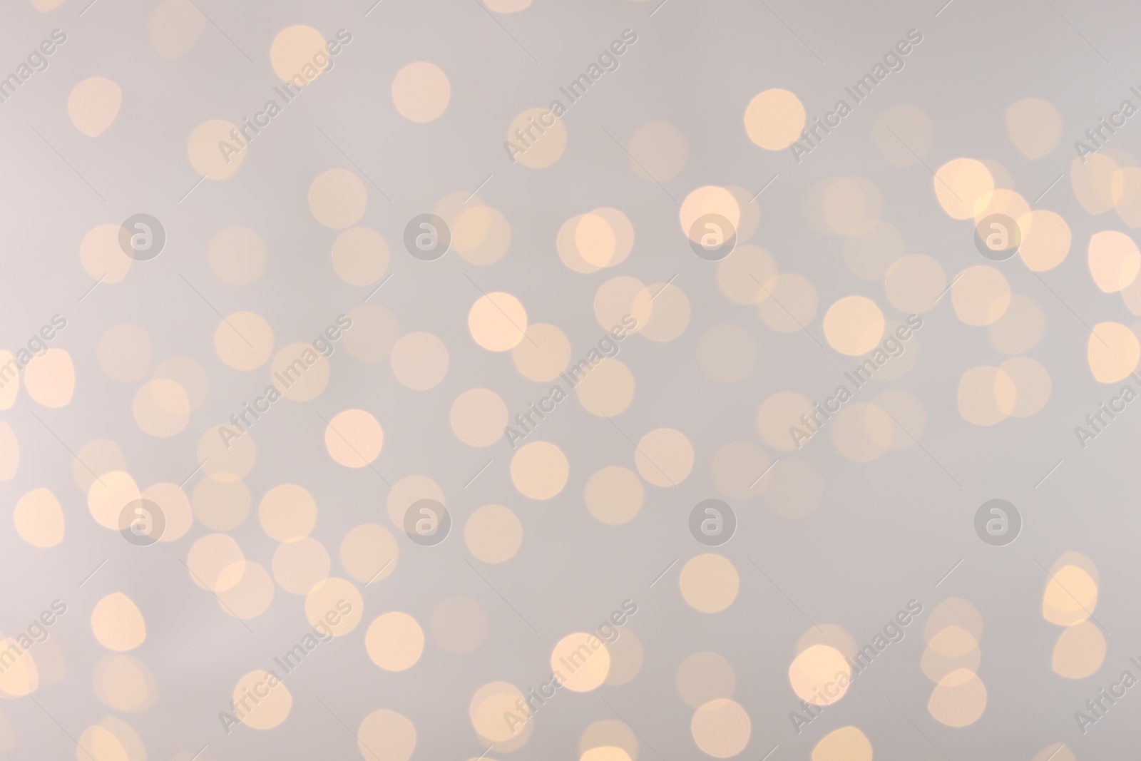 Photo of Blurred view of golden lights on light background, bokeh effect