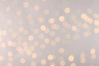 Photo of Blurred view of golden lights on light background, bokeh effect