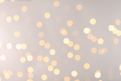 Photo of Blurred view of golden lights on light background, bokeh effect