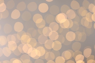 Photo of Blurred view of golden lights on light background, bokeh effect