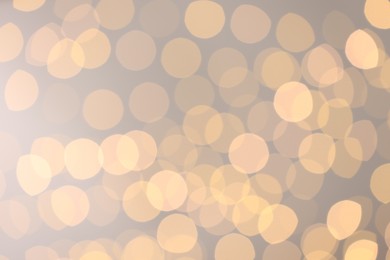 Photo of Blurred view of golden lights on light background, bokeh effect