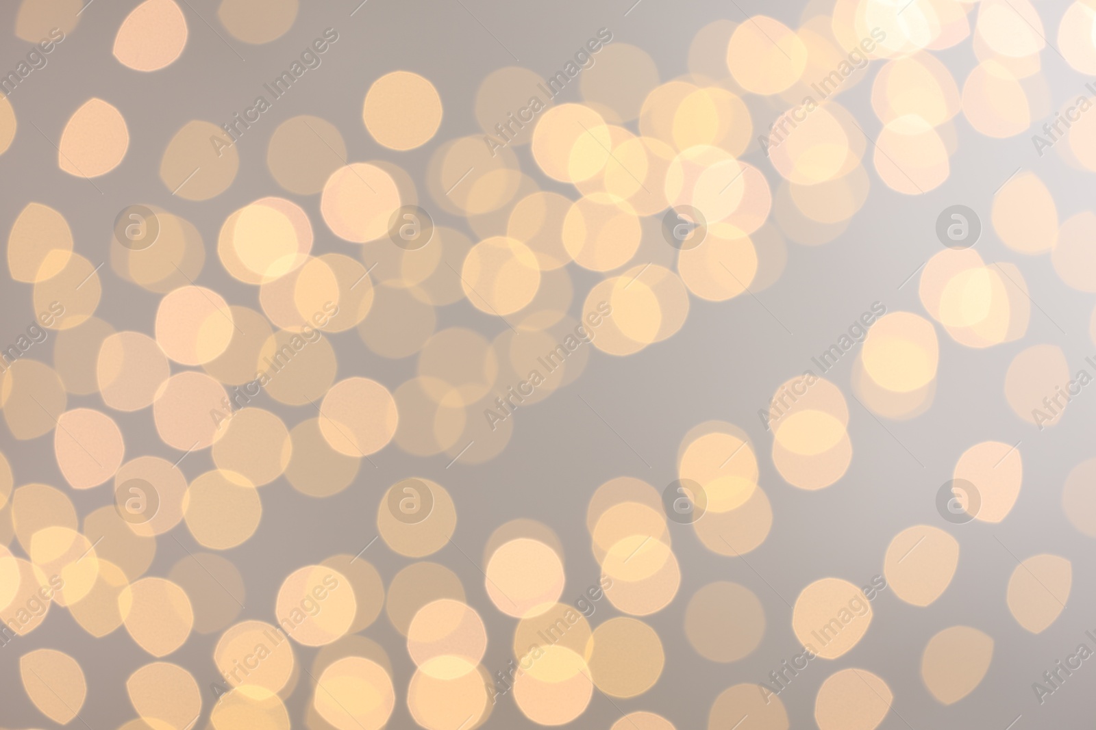 Photo of Blurred view of golden lights on light background, bokeh effect