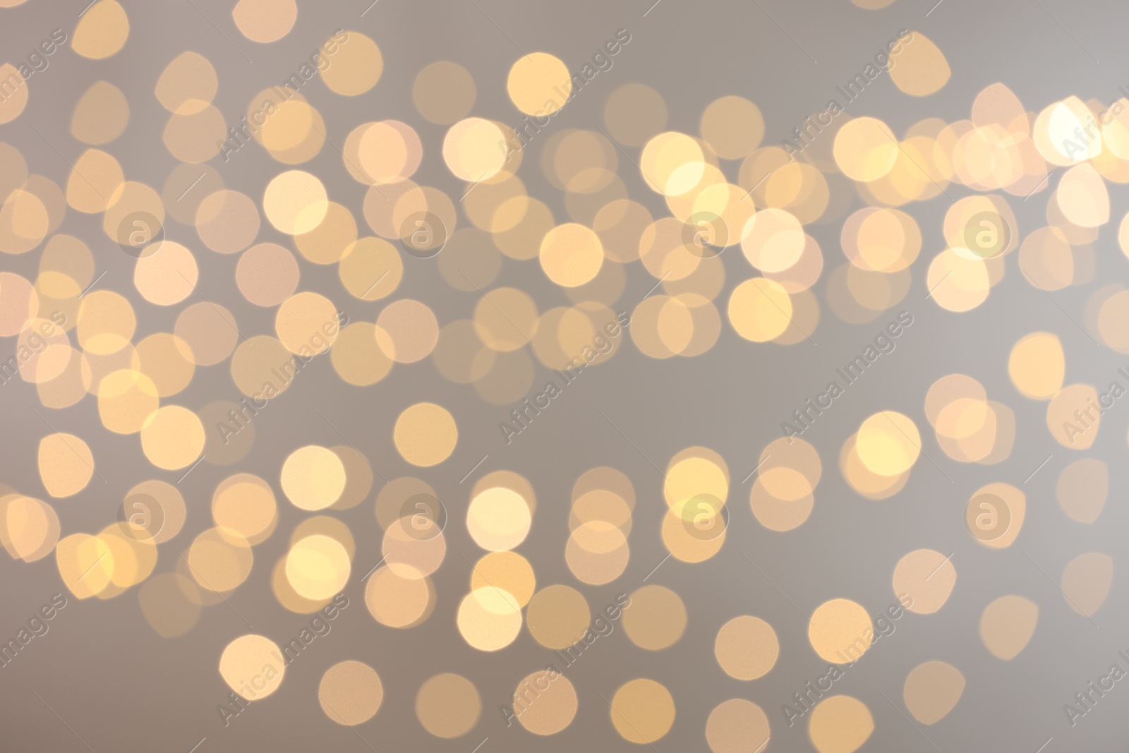 Photo of Blurred view of golden lights on light background, bokeh effect