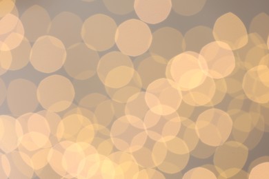 Photo of Blurred view of golden lights on light background, bokeh effect