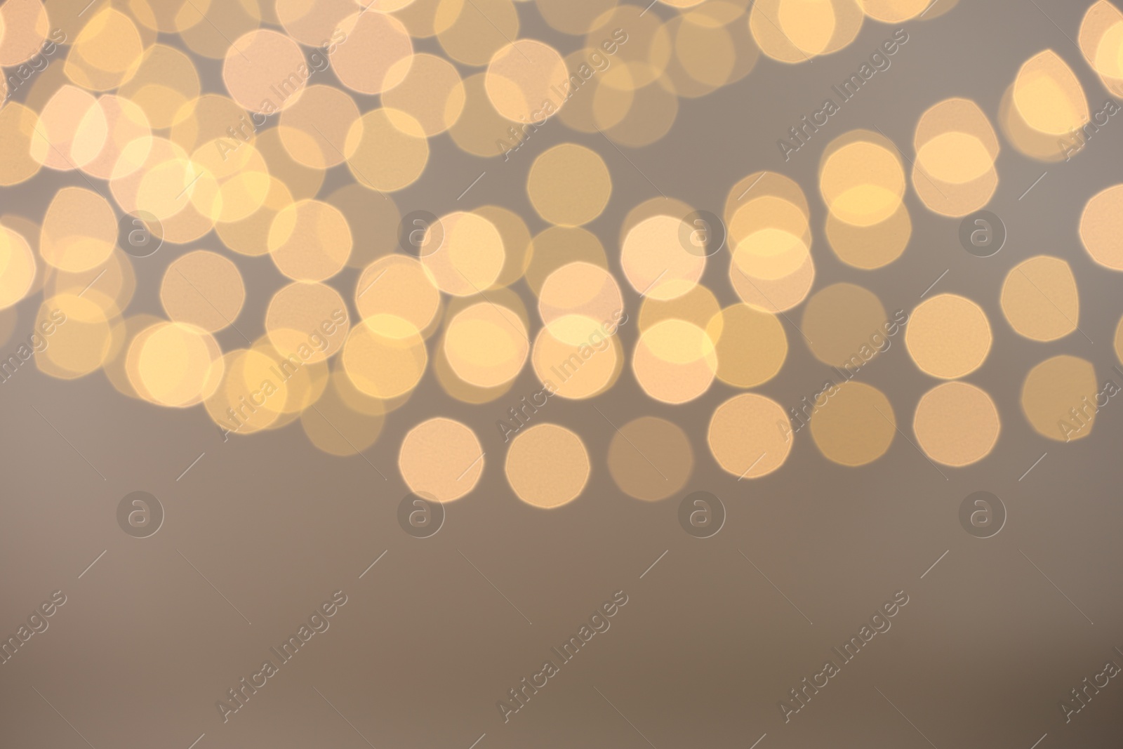 Photo of Blurred view of golden lights on light background, space for text. Bokeh effect