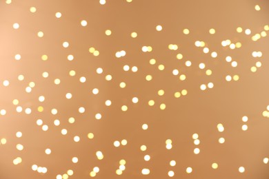 Photo of Blurred view of golden lights on light background, bokeh effect